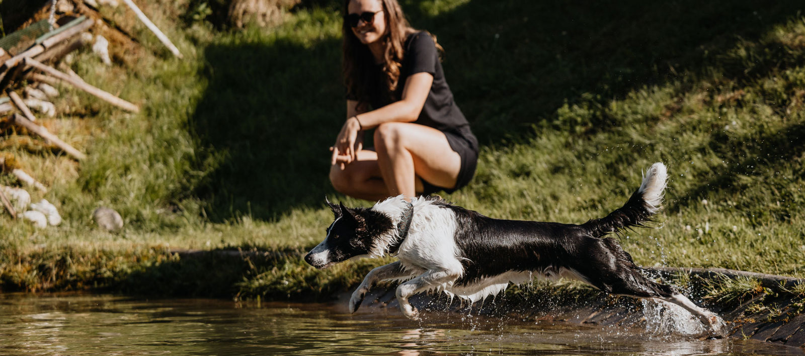 A dog plays in a mountain lake, mistress watches